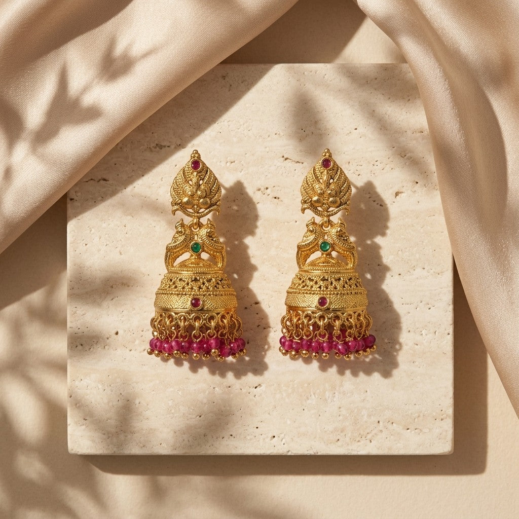 Lakx Fashion Lakshmi Jhumka earrings in gold-tone brass with green and ruby stones and pink bead fringe on stone base.