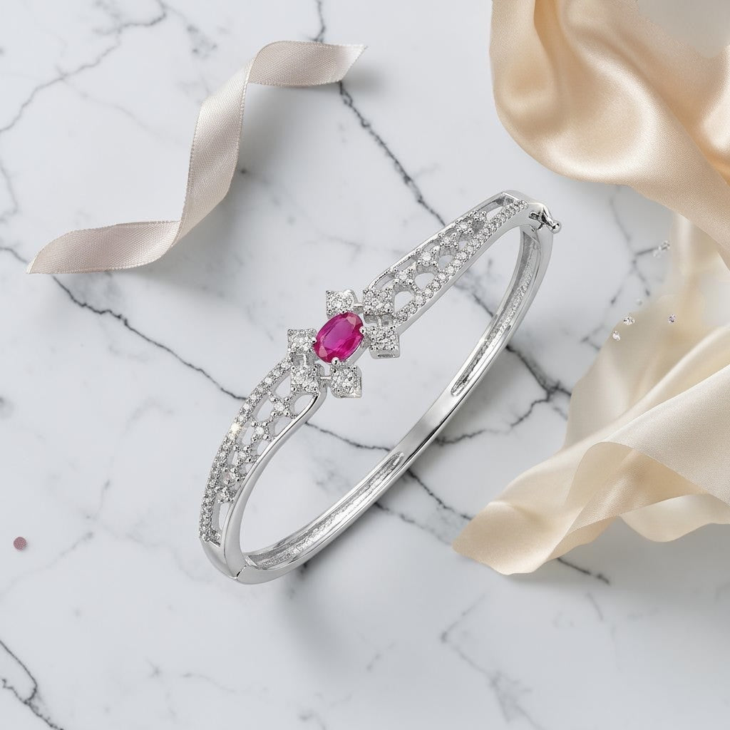Lakx Fashion rhodium-tone hinged kada with an oval pink stone and clear CZ lattice-work on a marble background.