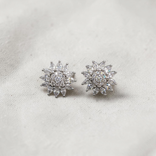Lakx Fashion silver tone floral stud earrings with clear AD cubic zirconia marquise petals on a black marble surface
