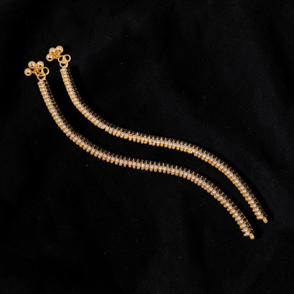 Lakx Fashion gold-toned anklets with alternating black and clear crystals and small ghungroo charms on marble surface.