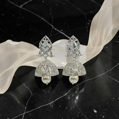 Lakx Fashion rhodium-tone floral jhumka earrings with white CZ stones and dangling faux pearls on a black surface.