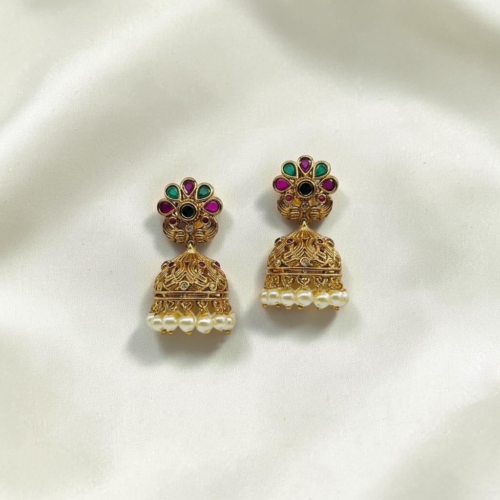 Lakx Fashion gold-tone brass jhumka earrings with floral studs, green and ruby stones, and dangling white pearls.