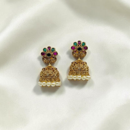 Lakx Fashion gold-tone brass jhumka earrings with floral studs, green and ruby stones, and dangling white pearls.