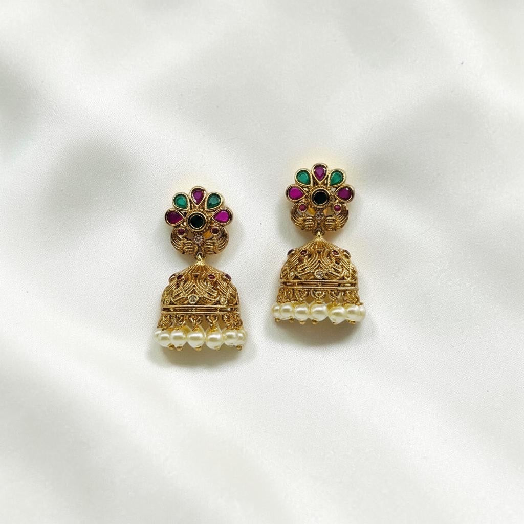 Lakx Fashion gold-tone brass jhumka earrings with floral studs, green and ruby stones, and dangling white pearls.