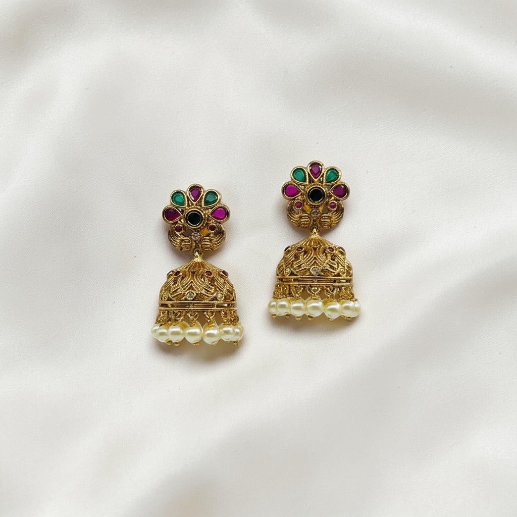 Lakx Fashion gold-tone brass jhumka earrings with floral studs, green and ruby stones, and dangling white pearls.
