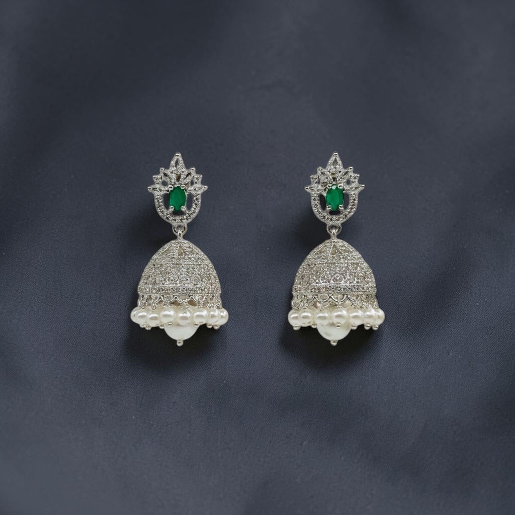 Lakx Fashion rhodium-tone jhumka earrings with green oval stones, white CZ accents, and dangling pearls on dark fabric.