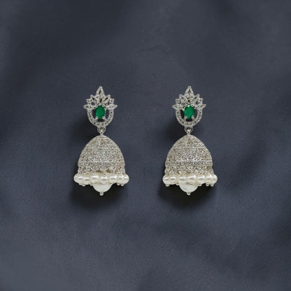Lakx Fashion rhodium-tone jhumka earrings with green oval stones, white CZ accents, and dangling pearls on dark fabric.
