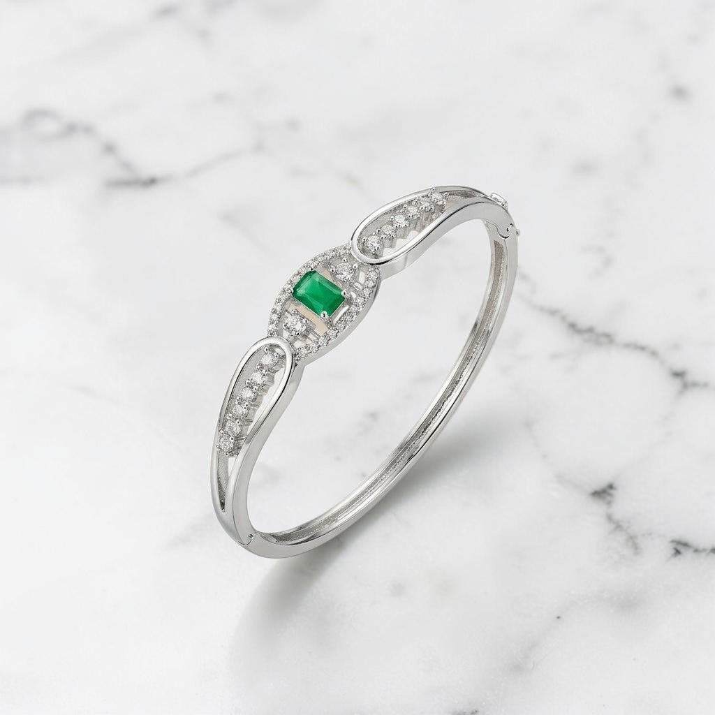 Lakx Fashion hinged brass kada bracelet with a central emerald-cut green stone and pavé-set clear stones.