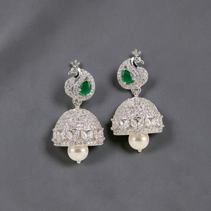 Lakx Fashion rhodium-tone jhumka earrings featuring peacock motifs, emerald green stones, diamonds, and pearl drops.