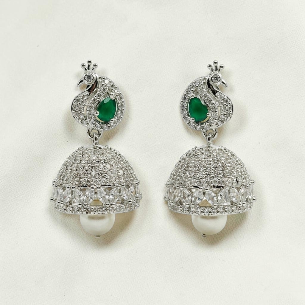 Lakx Fashion rhodium-tone jhumka earrings featuring a peacock motif, emerald green stones, diamonds, and pearl drops.
