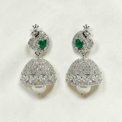 Lakx Fashion rhodium-tone jhumka earrings featuring a peacock motif, emerald green stones, diamonds, and pearl drops.