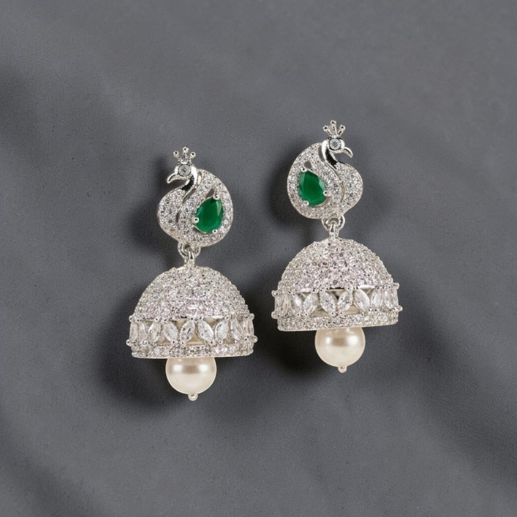 Lakx Fashion rhodium-tone jhumka earrings with peacock motifs, emerald green stones, American diamonds, and pearl drops.