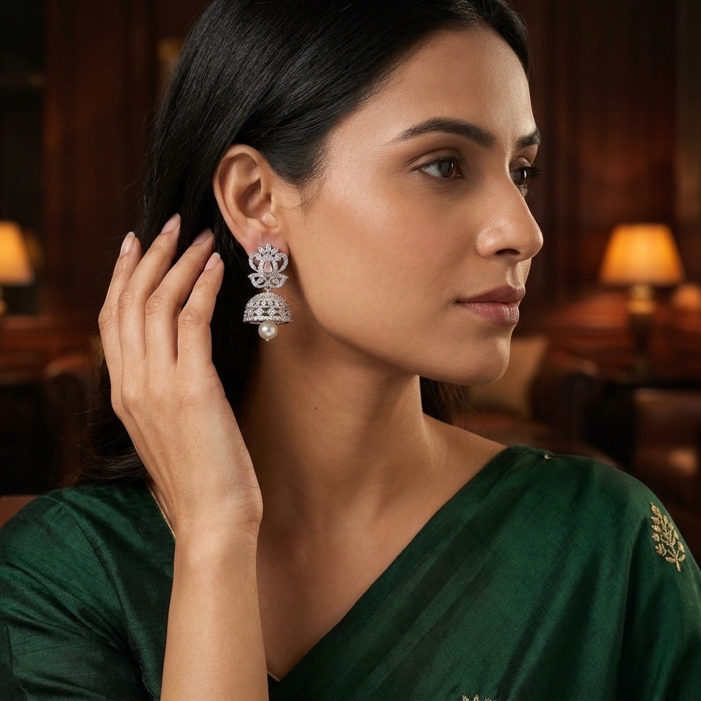 Lakx Fashion rhodium-tone jhumka earrings with pink stone, white CZ, and pearl drop worn by a woman in a green saree.