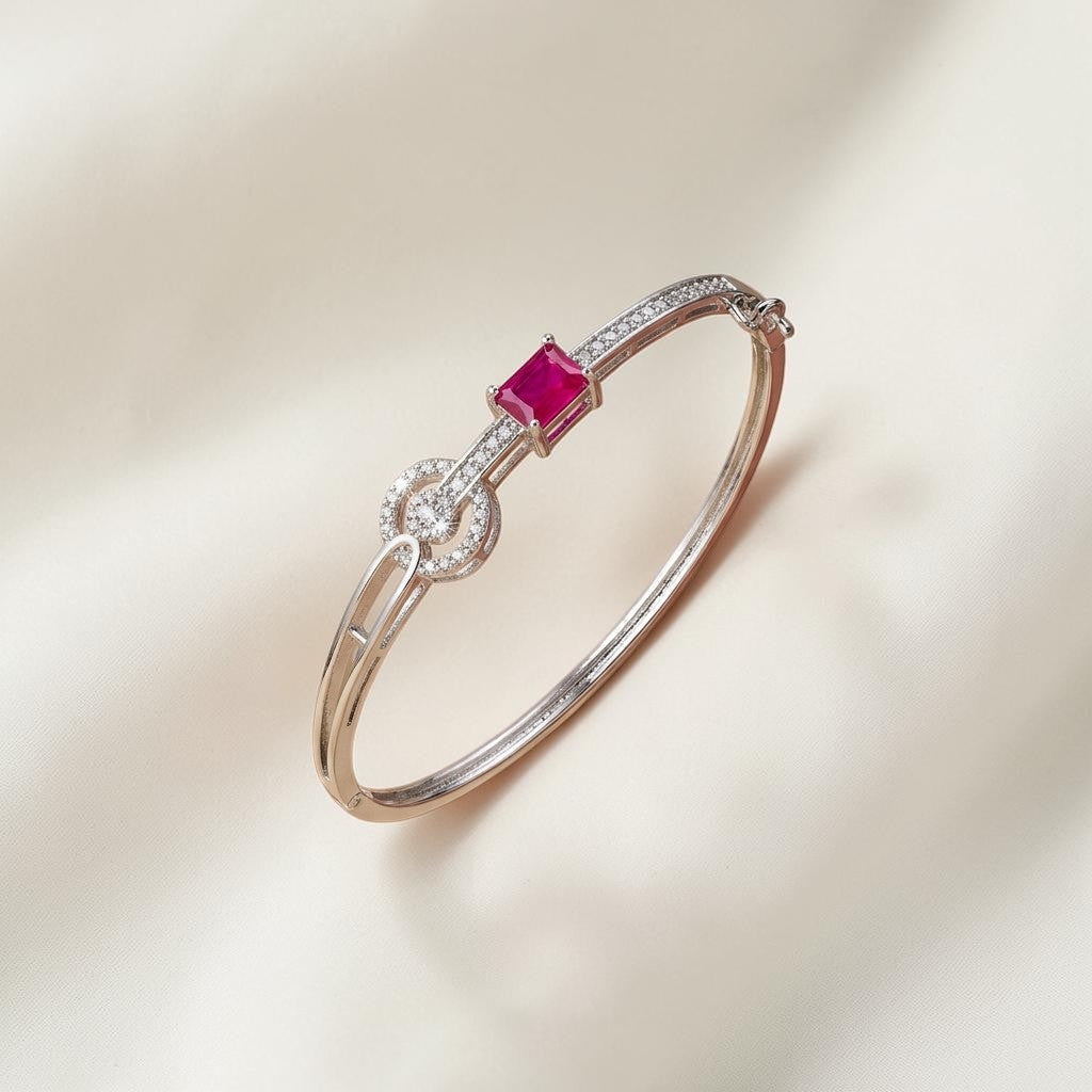 Lakx Fashion rhodium-tone brass bangle featuring a vibrant emerald-cut red stone and sparkling white CZ accents.