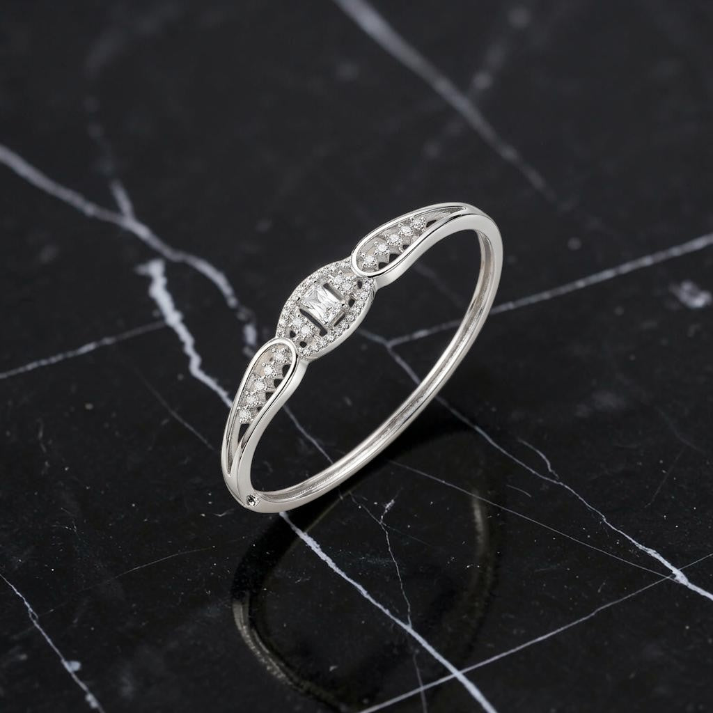 Lakx Fashion rhodium-tone brass hinged kada bracelet with a central emerald-cut stone and pavé-set clear CZ stones.