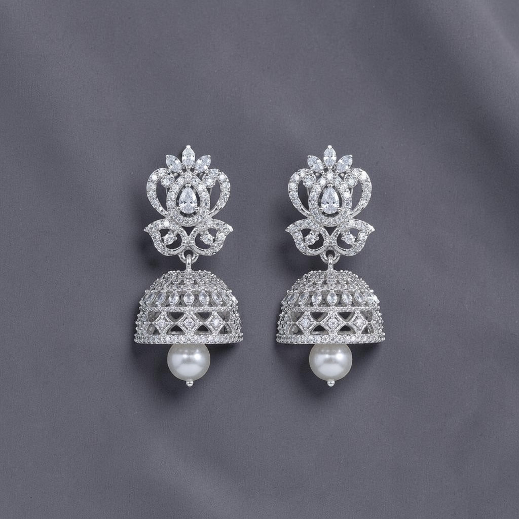 Lakx Fashion rhodium-tone brass jhumka earrings with white CZ stones and a dangling pearl drop on a dark background.