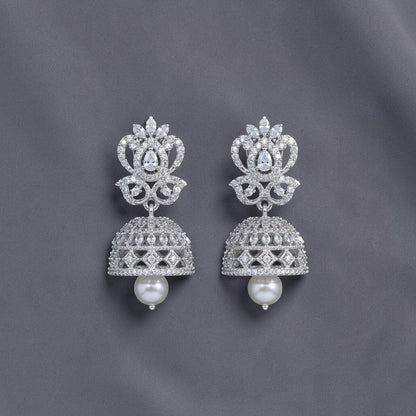 Lakx Fashion rhodium-tone brass jhumka earrings with white CZ stones and a dangling pearl drop on a dark background.