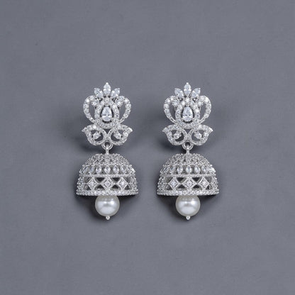 Lakx Fashion rhodium-tone brass jhumka earrings with white CZ stones and a dangling pearl drop on a dark background.
