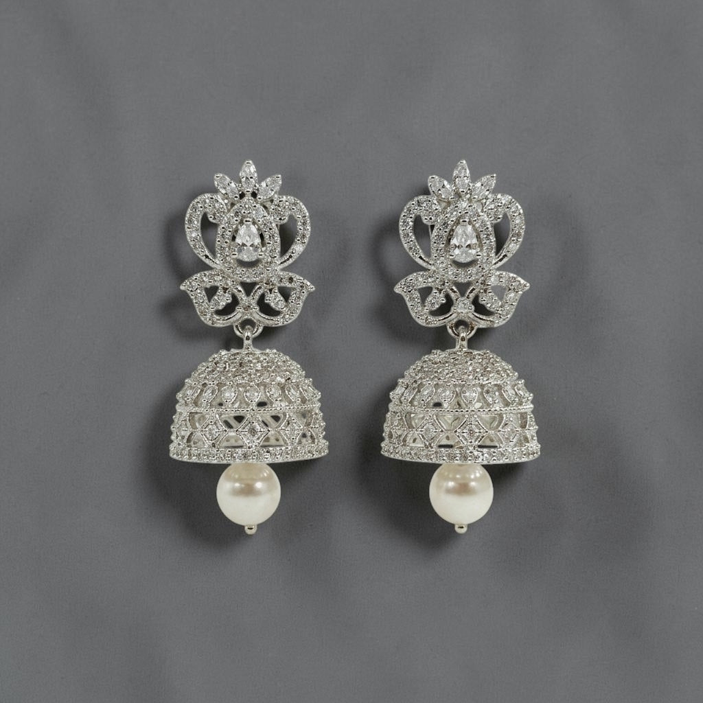 Lakx Fashion rhodium-tone brass jhumka earrings with white CZ stones and a dangling pearl drop on a grey background.