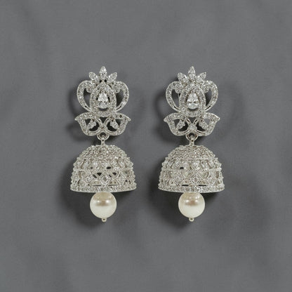 Lakx Fashion rhodium-tone brass jhumka earrings with white CZ stones and a dangling pearl drop on a grey background.