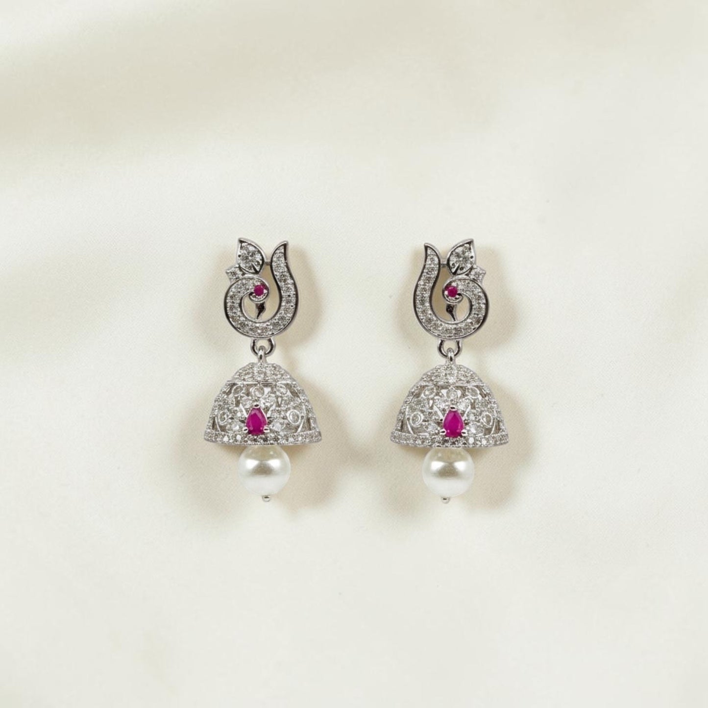 Lakx Fashion rhodium-tone jhumka earrings with peacock motifs, ruby-colored stones, white CZ, and pearl drops.